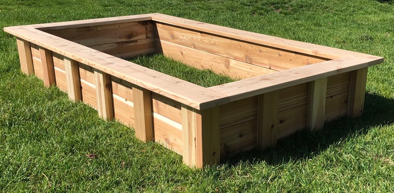 Puede incluir: Un lecho elevado de jard&iacute;n rectangular de madera de cedro. El lecho est&aacute; sobre un c&eacute;sped verde.