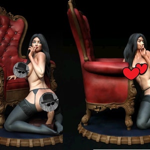 May include: A woman in lingerie poses on a red velvet chair with ornate carvings. She is wearing a black garter belt and stockings. The chair is on a wooden base with a blue velvet cushion.