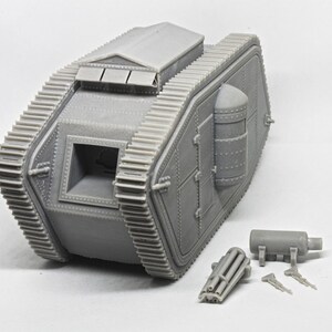 Puede incluir: Un modelo de pl&aacute;stico gris de un tanque de la Primera Guerra Mundial con un dise&ntilde;o detallado. El tanque tiene una gran abertura rectangular en la parte delantera y una abertura redonda m&aacute;s peque&ntilde;a en la parte trasera. El tanque est&aacute; sentado sobre una superficie blanca. El modelo est&aacute; desmontado e incluye un ca&ntilde;&oacute;n separado y otras partes.