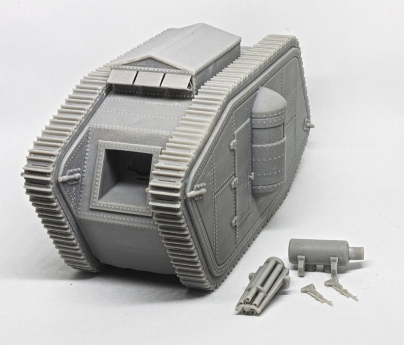 Puede incluir: Un modelo de pl&aacute;stico gris de un tanque de la Primera Guerra Mundial con un dise&ntilde;o detallado. El tanque tiene una gran abertura rectangular en la parte delantera y una abertura redonda m&aacute;s peque&ntilde;a en la parte trasera. El tanque est&aacute; sentado sobre una superficie blanca. El modelo est&aacute; desmontado e incluye un ca&ntilde;&oacute;n separado y otras partes.