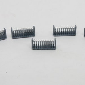 Puede incluir: Cinco secciones de valla de pl&aacute;stico gris con detalles blancos. Cada secci&oacute;n tiene 12 barras verticales con una abertura rectangular en el centro de cada barra.