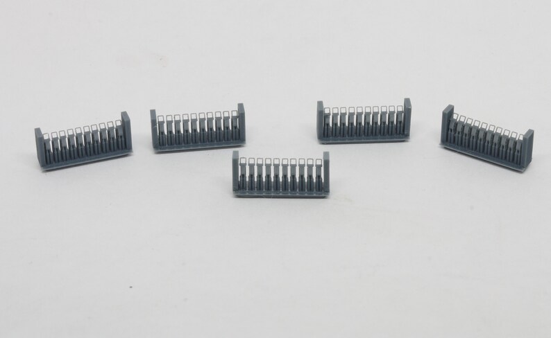 Puede incluir: Cinco secciones de valla de pl&aacute;stico gris con detalles blancos. Cada secci&oacute;n tiene 12 barras verticales con una abertura rectangular en el centro de cada barra.