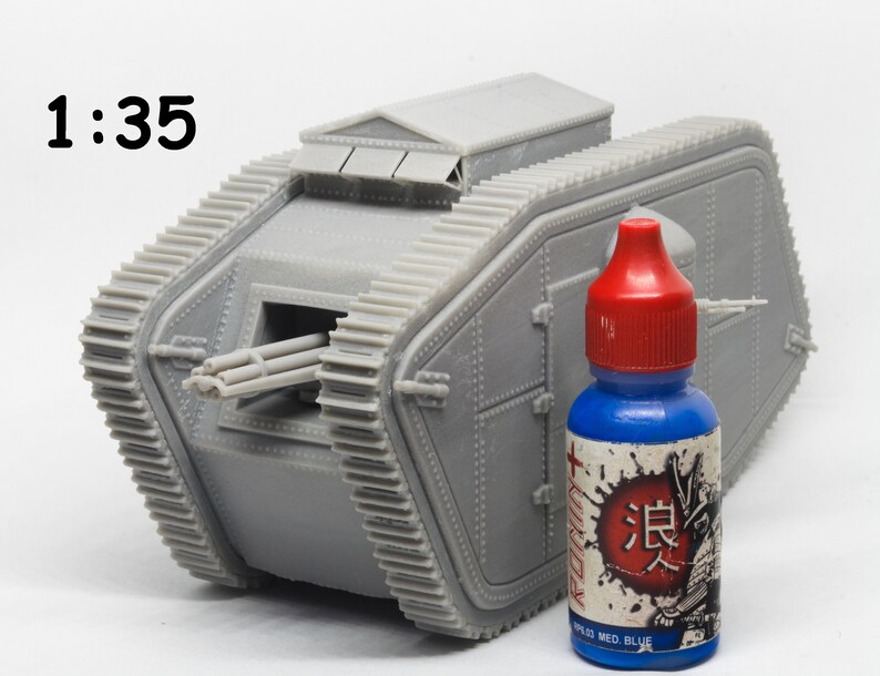 Puede incluir: Un modelo de pl&aacute;stico gris de un tanque de la Primera Guerra Mundial, a escala 1:35, con una botella de pintura azul a su lado. La botella tiene una tapa roja y una etiqueta de estilo japon&eacute;s con la palabra "浪人" en rojo.