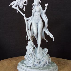 May include: A gray, detailed, 3D printed figurine of a female figure with a skeletal scythe, standing on a base with skulls and ghostly figures.