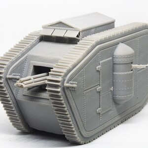 Puede incluir: Un modelo gris de un tanque de la Primera Guerra Mundial con un ca&ntilde;&oacute;n grande y una ametralladora m&aacute;s peque&ntilde;a en la parte trasera. El tanque tiene un dise&ntilde;o distintivo en forma de diamante y est&aacute; hecho de pl&aacute;stico.