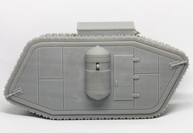 Puede incluir: Un modelo gris de un tanque de la Primera Guerra Mundial con un casco redondeado y blindado y una peque&ntilde;a torreta en la parte superior. El tanque tiene un sistema de orugas y una escotilla en el lateral.