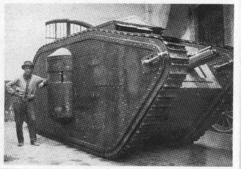 Puede incluir: Una fotograf&iacute;a en blanco y negro de un veh&iacute;culo grande y blindado con un hombre de pie junto a &eacute;l. El veh&iacute;culo tiene una parte delantera grande y redondeada y una serie de orugas en los lados. El hombre lleva un sombrero y un abrigo.