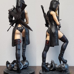 May include: A black and silver action figure of a female character wearing a black leather outfit, thigh-high boots, and a hooded cloak. She is holding a sword in one hand and a gun in the other. The figure is standing on a base with a broken piece of machinery.