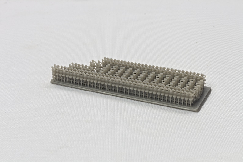 Puede incluir: Primer plano de una maqueta de una fila de sillas impresa en 3D. Las sillas est&aacute;n dispuestas en una cuadr&iacute;cula y est&aacute;n hechas de pl&aacute;stico gris claro.