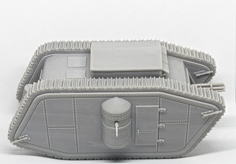 Puede incluir: Un modelo de pl&aacute;stico gris de un tanque de la Primera Guerra Mundial. El tanque tiene una torreta grande y rectangular en la parte superior y una torreta cil&iacute;ndrica m&aacute;s peque&ntilde;a en el lateral. El tanque tiene orugas en ambos lados y una escotilla grande y rectangular en la parte posterior.