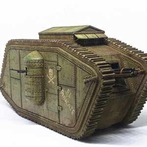 Puede incluir: Un modelo verde de un tanque de la Primera Guerra Mundial con una calavera y huesos cruzados pintados en el lateral. El tanque est&aacute; etiquetado como "EL PINECATE".