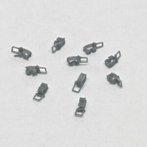 Puede incluir: Diez cierres o sujetadores de metal gris. Los cierres son peque&ntilde;os y tienen un dise&ntilde;o sencillo.