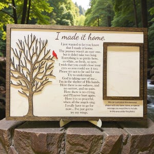 May include: Wooden memorial plaque with a tree design, a red bird, and a photo frame. The text reads "I made it home" with a poem. The plaque is brown with a light wood background.