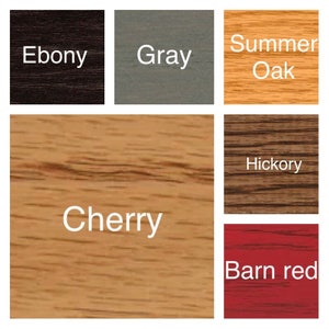May include: A color palette chart displaying six wood stain samples with labels: Ebony, Gray, Summer Oak, Cherry, Hickory, and Barn red. Each square shows a distinct wood grain texture and color, ranging from dark black to light tan and red.