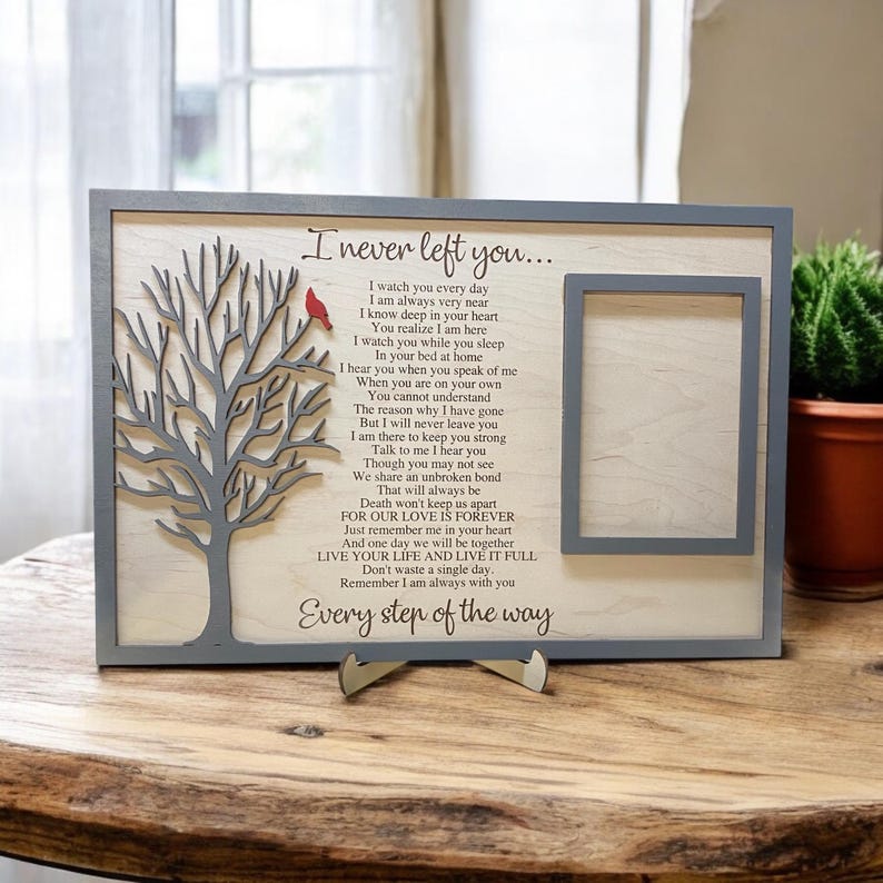 May include: A rectangular wooden memorial plaque with a gray frame, featuring a laser-cut gray tree with a small red cardinal, a photo frame cutout, and the poem I never left you printed in black text on a light wood background.