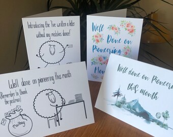 May include: Four greeting cards with different designs. One card features a sheep with the text "Introducing the 'I've written a letter without any mistakes dance!'". Another card features a sheep with the text "Well done on pioneering this month (Remember to thank the postman)". The third card features a floral design with the text "Well Done on Pioneering". The fourth card features a watercolor mountain scene with the text "Well done on pioneering this month".