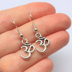 May include: A pair of silver Om symbol earrings with a hook closure.