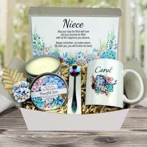 May include: A gift basket containing a white mug with a floral design and the name "Carol", a candle, a spoon, and a card with the word "Niece" and a message. The candle is labeled "Peaceful Zen". The spoon has the name "Carol" on it.