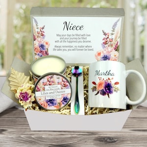 May include: A gift basket containing a mug with the name "Martha", a candle, a decorative spoon, and a card with the word "Niece" and a message. The mug and card are decorated with floral designs. The candle is labeled "Lilies and Daisies".