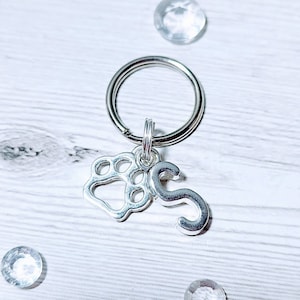 May include: Silver key chain with a paw print charm and the letter S.