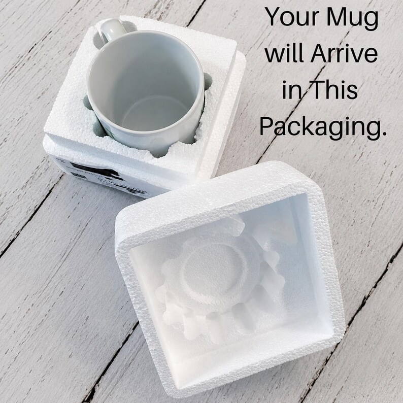 May include: A white ceramic mug nestled inside a two-piece white polystyrene foam protective shipping container. The top piece of the foam packaging is removed and placed beside the base. Text reads: Your Mug will Arrive in This Packaging.