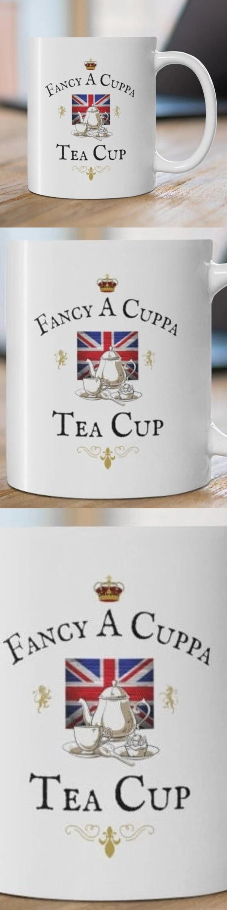 May include: A white ceramic mug featuring a graphic of a Union Jack flag, a silver teapot, a teacup, and a cupcake. The text reads "Fancy A Cuppa" above the flag and "Tea Cup" below, with a small crown icon at the top and gold flourishes.