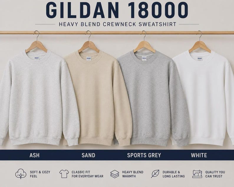 K&ouml;nnte beinhalten: Vier Gildan 18000 Heavy Blend Rundhals-Sweatshirts h&auml;ngen an einer Holzstange. Die Farben von links nach rechts sind Ash, Sand, Sports Grey und White. Jedes Sweatshirt hat lange &Auml;rmel, einen gerippten Rundhalsausschnitt und gerippte B&uuml;ndchen.
