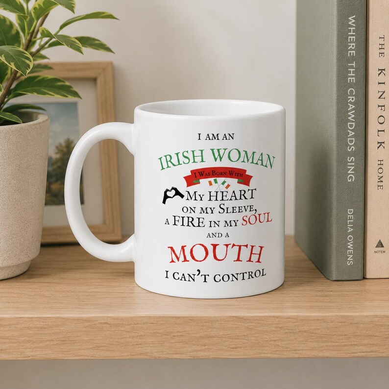 May include: A white ceramic mug featuring black, green, and red text that reads: I AM AN IRISH WOMAN I WAS BORN WITH MY HEART ON MY SLEEVE, A FIRE IN MY SOUL AND A MOUTH I CAN'T CONTROL, accompanied by a small heart-hand icon and two tiny flags.