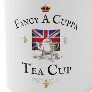 May include: A white ceramic mug featuring a graphic of a silver teapot, a teacup, a spoon, and a small cake. Behind the items is a Union Jack flag. Above the graphic is a crown and the text FANCY A CUPPA, and below is the text TEA CUP.