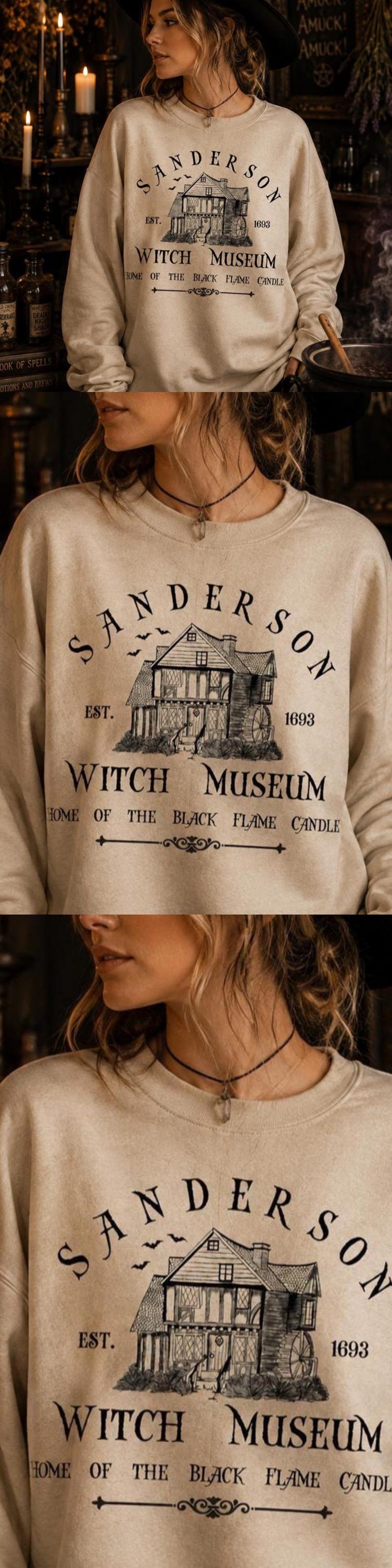 K&ouml;nnte beinhalten: Ein beigefarbenes Sweatshirt mit Rundhalsausschnitt und einem schwarzen Grafikdruck eines Hauses mit dem Text Sanderson Witch Museum, Est. 1693 und Home of the Black Flame Candle. Das Design zeigt zudem kleine fliegende Flederm&auml;use.