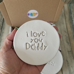 Puede incluir: Posavasos de cer&aacute;mica blanca con las palabras "i love you Daddy" en relieve.