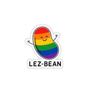 May include: A sticker featuring a cartoon bean in the colors of the rainbow pride flag. The bean has a smiling face and outstretched arms. The text "LEZ-BEAN" is printed below the bean in a black font.
