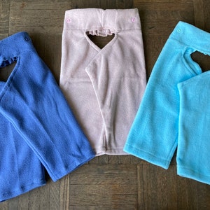 May include: Three fleece fabric neck gaiters in different colors: blue, pink, and light blue. Each gaiter has a heart-shaped opening in the front.
