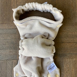 May include: A beige fleece cloth diaper with a white label that says "Best Bottom" and a white elastic waistband.