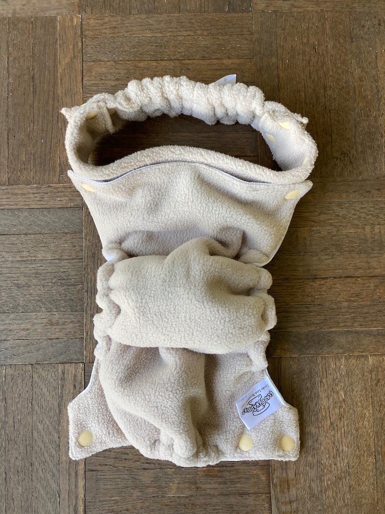 May include: A beige fleece cloth diaper with a white label that says "Best Bottom" and a white elastic waistband.