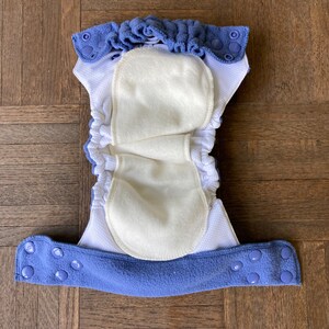 May include: A blue and white reusable cloth diaper with a white fleece lining and snap closures.
