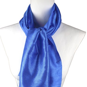 May include: A royal blue silk scarf with fringed edges. The scarf is draped around a white mannequin's neck.