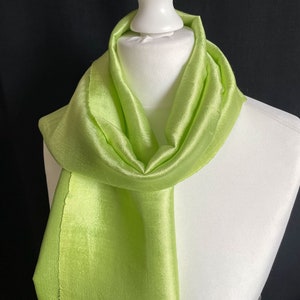 May include: A light green silk scarf draped on a white mannequin. The scarf is smooth and shiny.