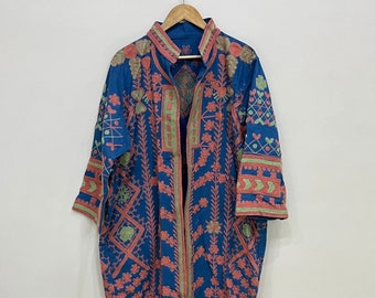 May include: A blue embroidered tunic with pink and green floral designs. The tunic has a collar and long sleeves.