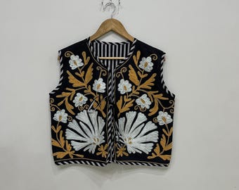 May include: A black sleeveless vest with a striped lining and floral embroidery in white and gold thread.