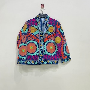 May include: A blue embroidered jacket with floral patterns in shades of pink, orange, yellow, and green. The jacket has a button closure and long sleeves.