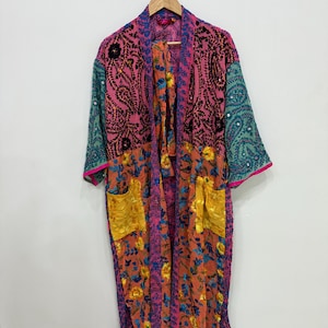 May include: A long, open-front robe with a vibrant floral and paisley design. The robe features a mix of pink, teal, and yellow fabrics, with pockets and trim in contrasting colors. The sleeves have a sequined detail.