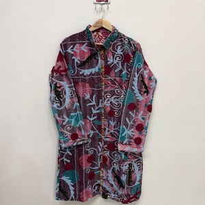 May include: A long-sleeved jacket featuring a dark purple base with a vibrant floral pattern in shades of red, teal, and light blue. The garment has a mandarin collar, a front button closure, and visible stitching throughout the fabric surface.