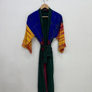 以下が含まれることがあります： 深い緑色をベースに、胸元と袖に鮮やかな青と黄色のタイダイ柄があしらわれた長袖のローブ。ウエストには共布の結びベルトが付いており、前開きの縁にはダークグリーンのトリミングが施されています。