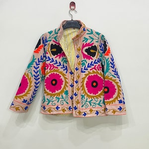 May include: A pink embroidered jacket with colorful floral patterns. The jacket has a mandarin collar and long sleeves.