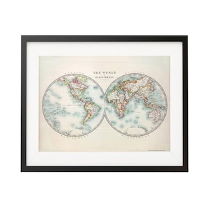 May include: A vintage world map print in a black frame. The map shows the world divided into hemispheres, with the Americas on the left and Europe, Asia, and Africa on the right. The map is printed in shades of blue, green, and brown, with red and yellow accents.