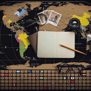 May include: A black and gold scratch-off world map with travel accessories. The map includes a notebook, pencil, camera, magnifying glass, and eyeglasses. The map has a section of country flags at the bottom. The text "LANDMASS" is visible.