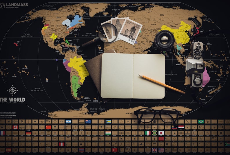 May include: A black and gold scratch-off world map with travel accessories. The map includes a notebook, pencil, camera, magnifying glass, and eyeglasses. The map has a section of country flags at the bottom. The text "LANDMASS" is visible.