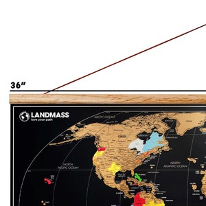 May include: A black world map with gold foil detailing, measuring 36 inches wide. The map features the text "LANDMASS love your path" and includes labels for oceans and continents. The map is mounted on a wooden frame.