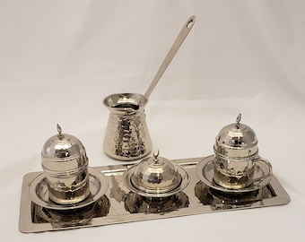 May include: A silver Turkish coffee set with a hammered finish. The set includes a coffee pot, two cups, two saucers, and a sugar bowl. The set is displayed on a silver tray.